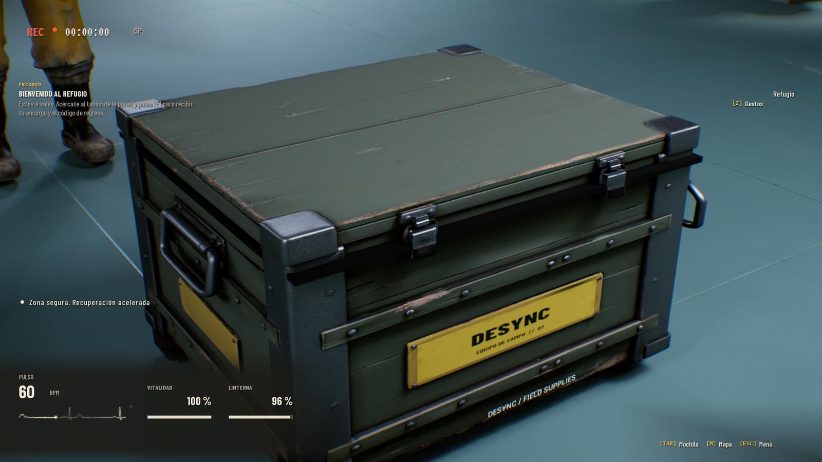 Caja militar verde marcada DESYNC EQUIPO DE CAMPO 07 junto a las botas de un sujeto.
